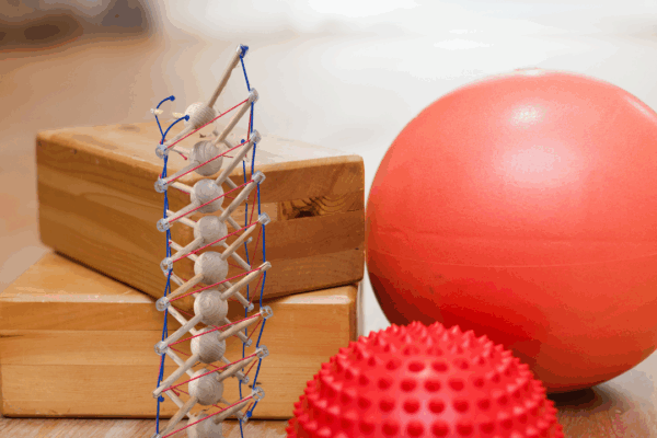 Yoga-Blöcke, Gymnastikball, Igelball und Wirbelsäulenmodell auf Holzfußboden