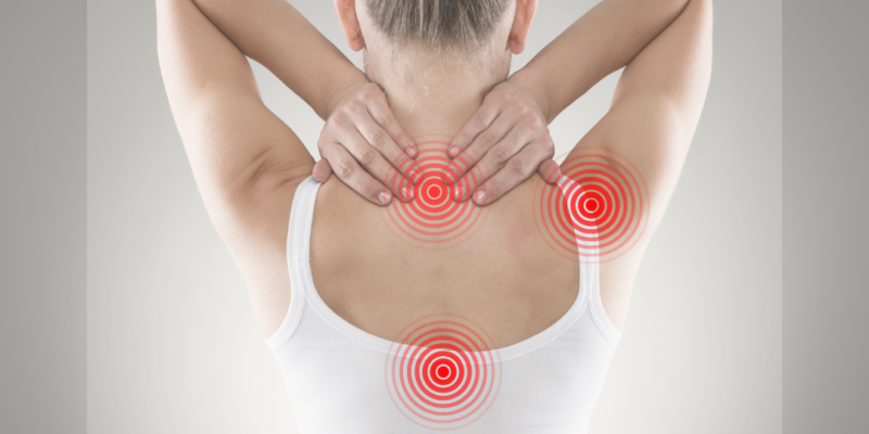 Frau von hinten greift sich in den Nacken, markierte Schmerzpunkte an Hals, Schultern und Rücken