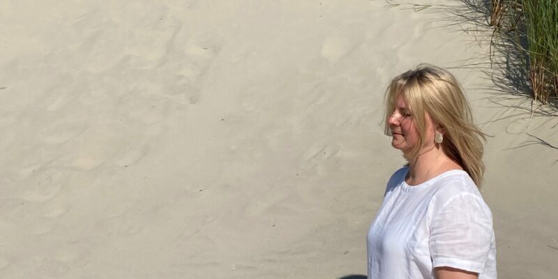 Frau Meditiert in einer Sanddühne bei Sonnenschein